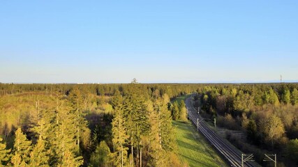 Poster - Aerial view: Train tracks run through the forest. Railway line illuminated in the golden light of the sunset near Munich and leads into the mountains