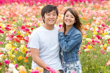 Young Japanese couple in a flower field looking at camera