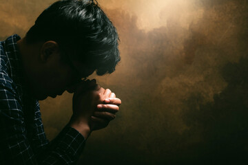 Wall Mural - Religious man praying to God resting his chin on his hands.His hands are praying for God's blessings.