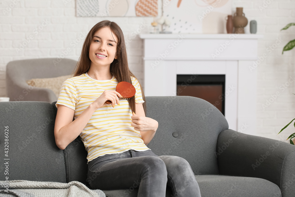 Beautiful young woman brushing hair at home
