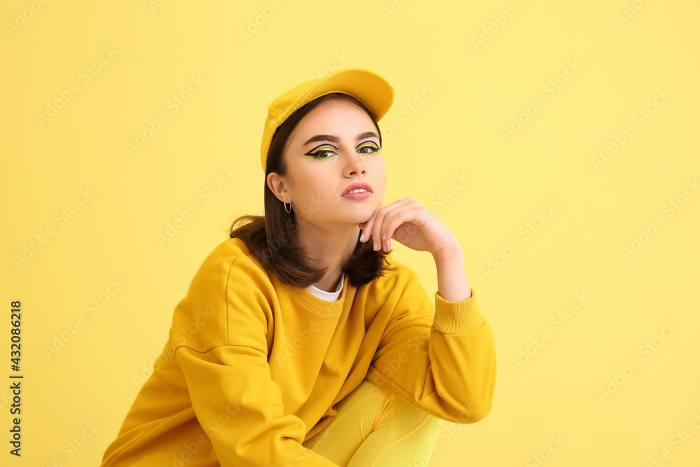 Stylish young woman on yellow background