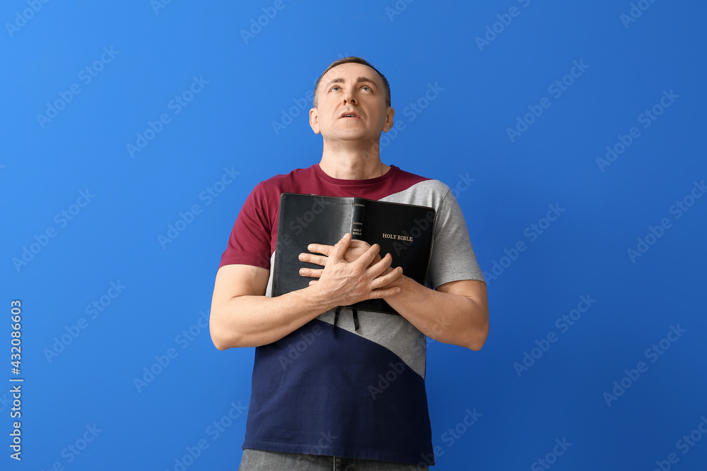 Man with Bible on color background