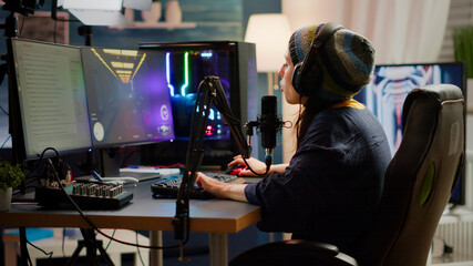 Canvas Print - Streamer putting on headphone and start talking into microphone with other players during online video game professional competition. Pro gamer sitting on gaming chair in streaming home studio with