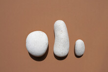 Three White Smooth Stones On A Beige Background. Top View, Place For Text.