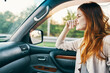 © SHOTPRIME STUDIO - happy woman with red hair in front seat of car touching face with hands cropped view