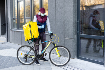 Wall Mural - Delivery Man standing with yellow thermo backpack for food delivery near the entrance home with empty space to copy paste