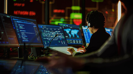Aufkleber - Multiethnic Female IT Technical Support Specialist Talking with a Client in Headphones and Working on Desktop Computer in Monitoring Control Room with Big Digital Screens with Server Blockchain Data.