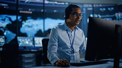 Aufkleber - Portrait of Professional IT Technical Support Specialist Working on Computer in Monitoring Control Room with Digital Screens. Employee Wears Headphones with Mic and Talking on a Call.