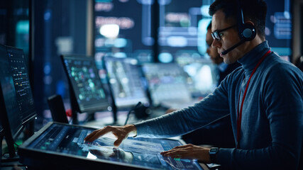 Aufkleber - Portrait of Professional IT Technical Support Specialist Working on Computer in Monitoring Control Room with Digital Screens. Employee Wears Headphones with Mic and Talking on a Call.
