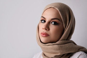 Wall Mural - Close-up portrait of young muslim woman wearing beige hijab. Space for text.