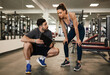Male personal trainer discussing fitness workout routine fit woman