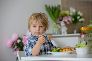 Little toddler child, blond boy, eating boiled vegetables, broccoli, potatoes and carrots with fried chicken meat at home