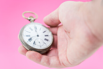 Wall Mural - Human hand holding old pocket watch on pink background