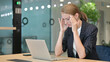 © stockbakers - Stressed Young Businesswoman with Laptop having Headache in Office