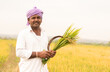 Happy Indian farmer Holding sickle and Paddy crop in hand - Concept good crop yields due to monsoon rains.