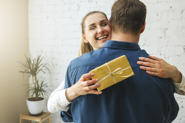 Wall Mural - thankful woman with gift box hugging husband at home. birthday or anniversary surprise