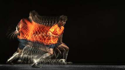 One Caucasian football soccer player in motion and action in mixed light on dark background.