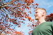 © KseniaJoyg - A young man against the sky and a blooming tree with red flowers, Los Angeles, Calfiornia