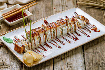 Sticker - The dragon roll with eel and green onion on beatiful plate on old wooden table. Chinese cuisine