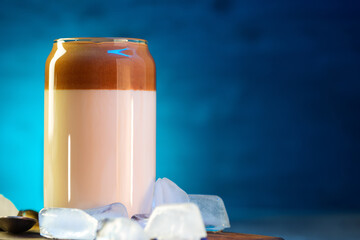 Wall Mural - Dalgona coffee is a stylish glass of summer refreshing drink with coffee and milk on a tiffany color background. Chunks of ice, copy space