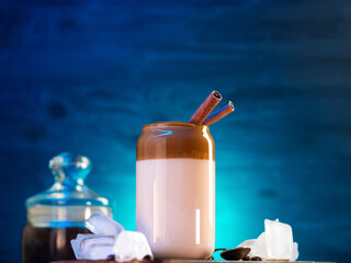 Wall Mural - Korean trend drink Dalgon coffee in a glass, chilled with ice. Cream cap, cinnamon sticks, whipped coffee with milk added
