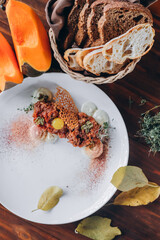 Wall Mural - Plate with delicious tartare, toasted bread and salad on a wooden table. Healthy gourmet French food made of raw meat.