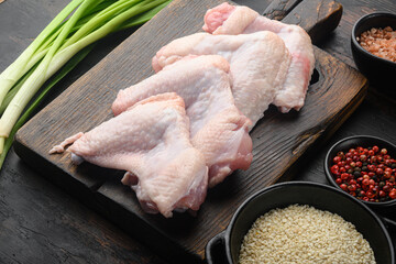 Wall Mural - Uncooked chicken wings with spices, and sesame, on wooden cutting board, on old dark  wooden table