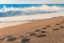 Close-up Of Blue Sea Water And Send With Footprints. Background, Copy Space