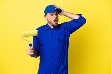 Painter Brazilian man isolated on yellow background doing surprise gesture while looking to the side