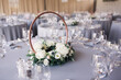 Floral wedding centrepiece on table with grey tablecloths and glasses