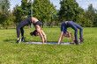 © Андрей Рыков - Photography of mother and daughter doing yoga together in summer city park. Bridge position (Chakrasana). Healthy lifestyle. Outdoor family sport theme.