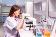 © atsarapong - Young woman researcher, doctor, scientist, looking through a microscope in a laboratory. Scientists are doing research