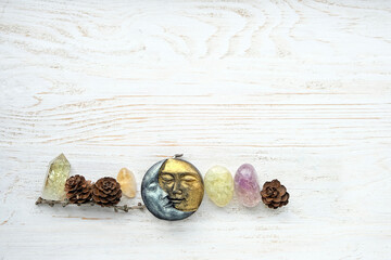 Wall Mural - symbolic moon wax candle, crystal gemstones and cones on white wooden background. life balance, esoteric, spiritual practice concept. flat lay. copy space