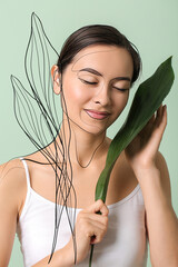 Wall Mural - Beautiful young woman with tropical leaves on color background