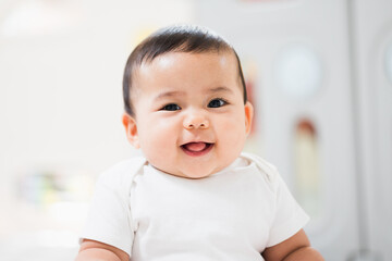 A cute baby wearing a white dress Stay with parents in the house