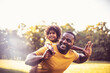Father carrying daughter piggyback. African American father and daughter having fun outdoors.