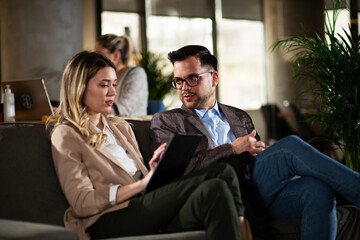 Wall Mural - Colleagues talking in the office. Businesswoman and businessman discussing work in office...