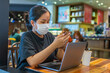 © Quang - Woman using smartphone and wearing medical mask at coffeeshop