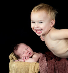 Canvas Print - Cheerful little Caucasian boy with his newborn baby brother on a basket