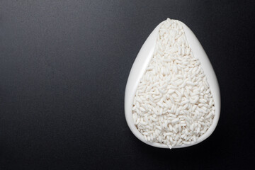 Wall Mural - Glutinous rice in a ceramic spoon on black background. Top view.