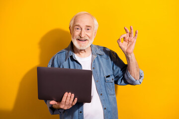 Sticker - Portrait of optimistic nice grey beard old man show okey hold laptop wear shirt isolated on orange background