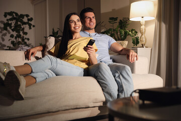 Canvas Print - Couple watching movie with popcorn on sofa at night