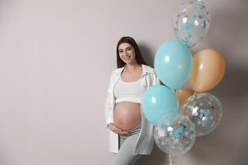 Sticker - Happy pregnant woman with balloons near grey wall. Baby shower party