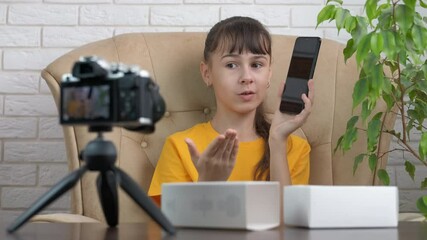 Child advertise the phone. A child vlogger show her smartphone on video from home on internet.