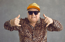 Cool Retired Gangsta Granddad Flexing To Rap Music. Portrait Of Funny Weird Active Rich Senior Man In Baseball Cap, Trendy Eyeglasses And Leopard Patterned Party Shirt Posing And Having Fun In Studio