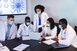 © Wavebreak Media - Team of diverse doctors wearing face mask discussing together over laptop in the meeting room