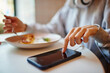 © BullRun - Unrecognizable female tapping on touchscreen of modern cellphone gadget during healthy breakfast in cafe interior,selective focus on digital smartphone technology used for online browsing in cafeteria