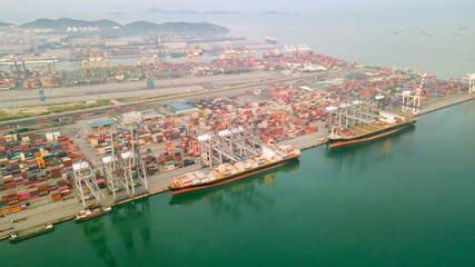 Wall Mural - Aerial drone view above dockyard. Cargo vessel is loading containers. Professional business logistics and transportation of cargo ship.