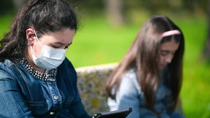 Sticker - Two young girls wearing masks outdoor seated on the bench in covid-19 pandemic