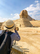 A girl in a straw hat takes pictures of Sphinx in Giza